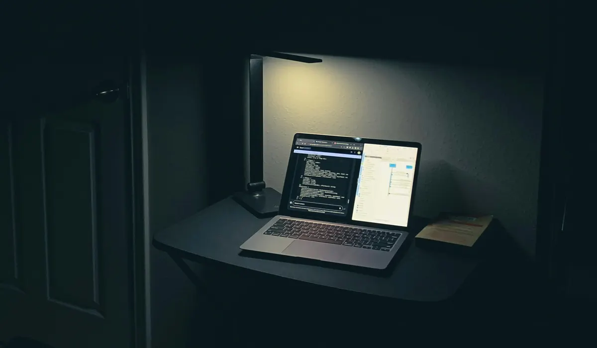 A laptop under a desk lamp in a dark room with code on the screen, the late-night kubectl fix GitOps has to account for
