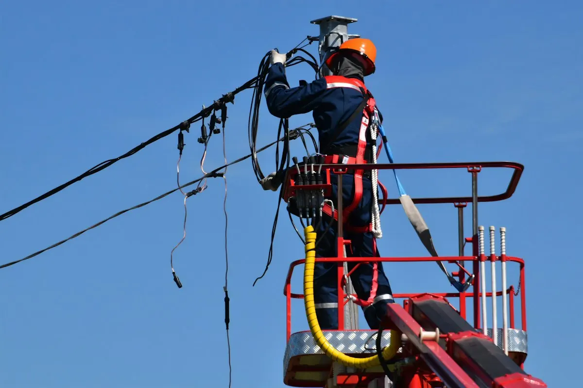 Utility worker repairing overhead power lines, the kind of outage that reboots a Kubernetes node with expired certificates