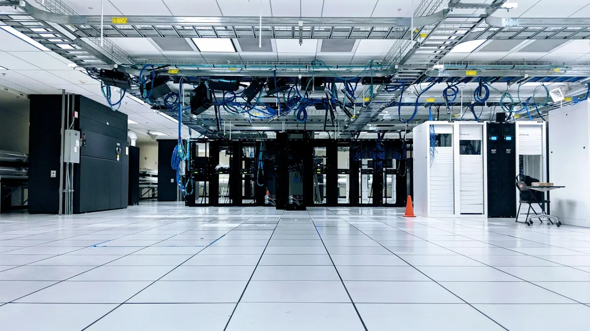 Cold aisle in a colocation data centre, rows of racks either side of a raised floor